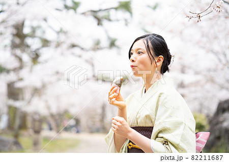 桜餅をおいしそうに食べながら観光している女性 82211687