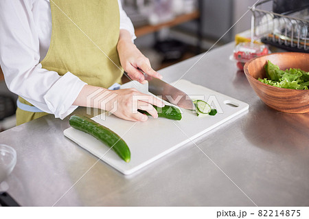 きゅうりを包丁で切るエプロン姿の若い女性 きゅうりを包丁で切るエプロン姿の若い女性 82214875
