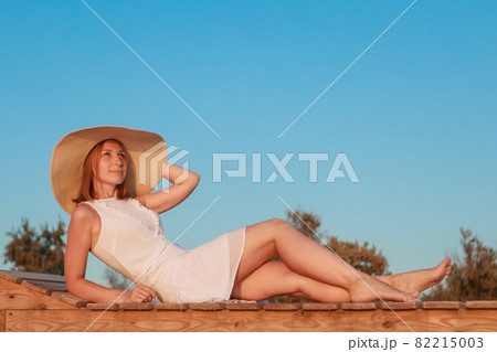 journey to the sea. a girl in a dress and hat is walking along the beach. a tourist walks along the sea coast. hot trips during the holiday period. copy space journey to the sea. a girl in a dress and hat is walking along the beach. a tourist walks along the sea coast. hot trips during the holiday period. copy space 82215003