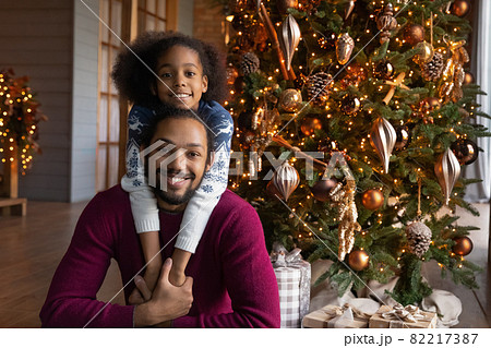 Portrait of biracial dad and daughter near fir tree 82217387