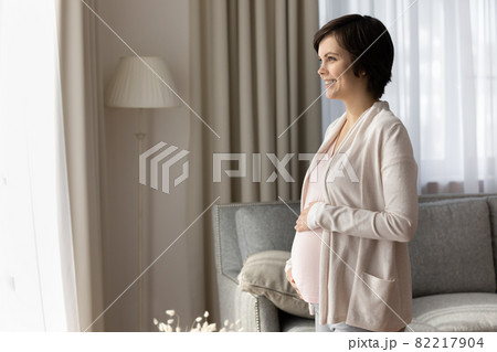 Carefree young expectant mother look at distance full of dreams Carefree young expectant mother look at distance full of dreams 82217904