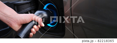 Woman charging car using electric plug closeup Woman charging car using electric plug closeup 82218365