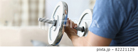 Man hand lifts heavy dumbbell while swinging biceps 82221129