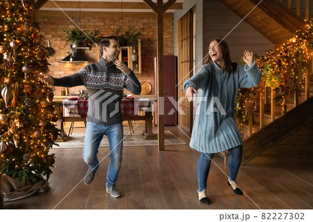 Overjoyed crazy young married family couple dancing near Christmas tree. 82227302