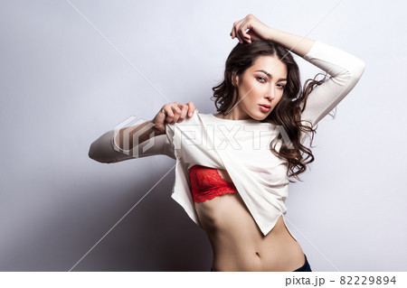 model posing in bra and undressing her white t shirt and looking at camera with passion. model posing in bra and undressing her white t shirt and looking at camera with passion. 82229894