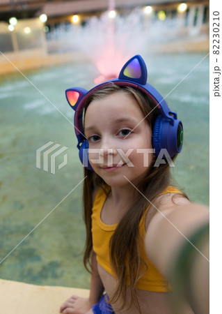 Schoolgirl preteen resting at dusk by fountain 82230210