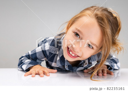 Close-up cute beautiful little girl looking at camera, making faces isolated on gray studio background. Human emotions, facial expression concept. 82235161