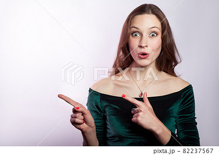 Portrait of surprised shocked woman with classic green dress showing empty space with finger. Portrait of surprised shocked woman with classic green dress showing empty space with finger. 82237567