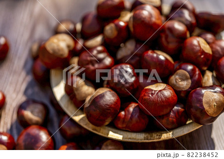 Chestnut in a plate on a brown wooden table. Autumn still life with bright horse chestnuts on wooden background Chestnut in a plate on a brown wooden table. Autumn still life with bright horse chestnuts on wooden background 82238452
