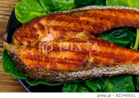 Grilled salmon steak with spinach on wooden table Grilled salmon steak with spinach on wooden table 82240031