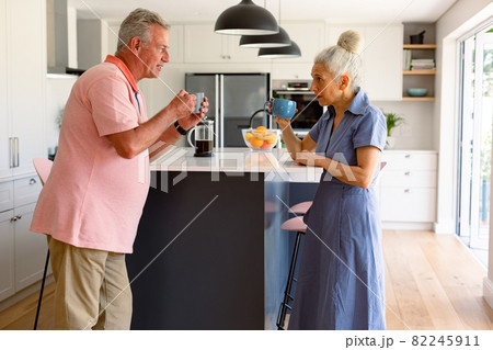 Caucasian senior couple drinking coffee together and talking in kitchen Caucasian senior couple drinking coffee together and talking in kitchen 82245911