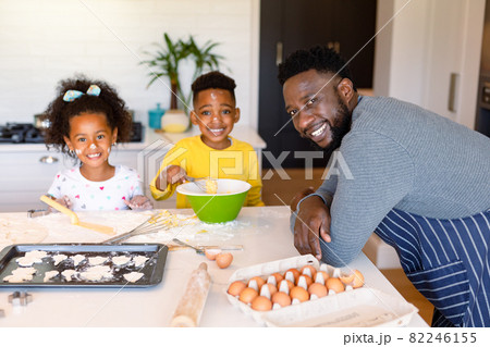 Happy african american father and siblings baking together in kitchen Happy african american father and siblings baking together in kitchen 82246155