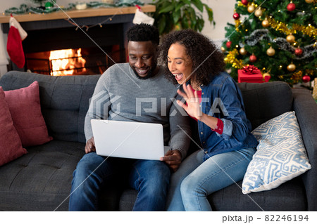Happy african american couple having video call on laptop, christmas decorations in background Happy african american couple having video call on laptop, christmas decorations in background 82246194