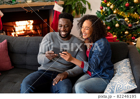 Happy african american couple having video call on smartphone, christmas decorations in background Happy african american couple having video call on smartphone, christmas decorations in background 82246195