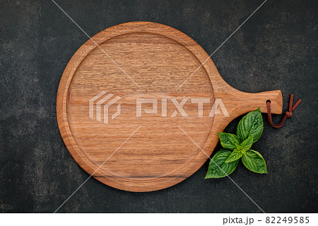 Empty wooden pizza platter set up on dark concrete. Pizza tray on dark concrete background flat lay and copy space. Empty wooden pizza platter set up on dark concrete. Pizza tray on dark concrete background flat lay and copy space. 82249585
