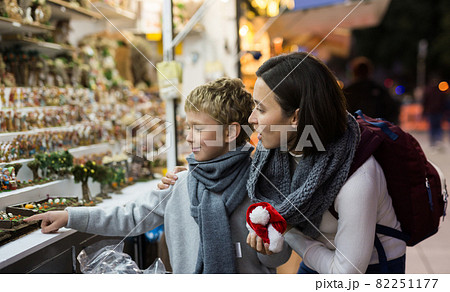 Tween boy with mother looking for Christmas decorations on street market Tween boy with mother looking for Christmas decorations on street market 82251177