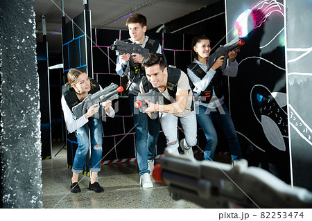 Cheerful Laser tag players young mens and womens playing in teams in dark laser tag station 82253474