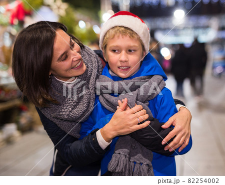 Happy tween boy with mom during shopping at Christmas fair Happy tween boy with mom during shopping at Christmas fair 82254002