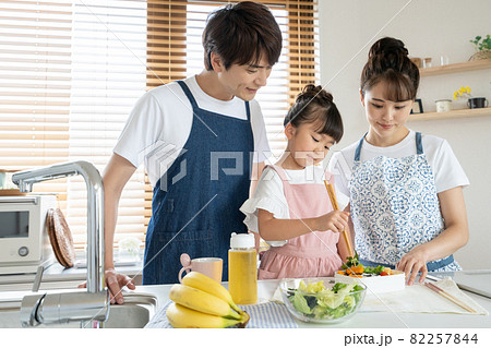 キッチンでお弁当を作る小学生の女の子とパパとママ 82257844