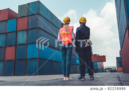Industrial worker works with co-worker at overseas shipping container yard 82258986