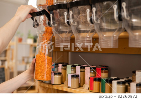 A man fills a jar with red lentils. Selling bulk goods by weight in an eco store. Trade concept without plastic packaging 82260872