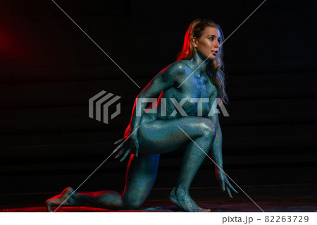 Gorgeous naked brunette posing painted in turquoise sequins. 82263729