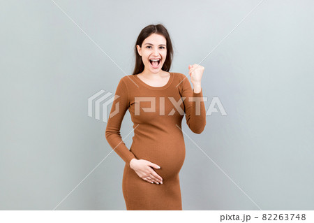 Young beautiful pregnant woman on isolated colored background celebrating surprised and amazed for success with arms raised and open eyes. Winner concept 82263748