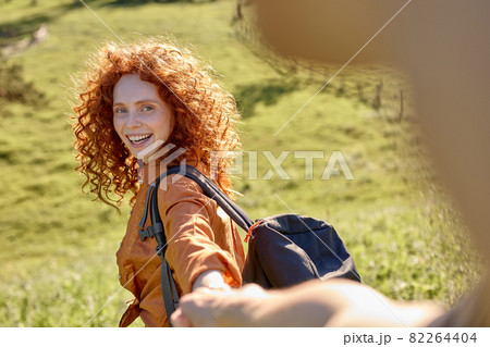 Follow me. Beautiful curly woman takes man's hand, leads in the forest to hike Follow me. Beautiful curly woman takes man's hand, leads in the forest to hike 82264404