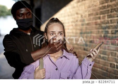 Criminal stalking female alone in a dark street alley, closing her mouth, ask to keep silence Criminal stalking female alone in a dark street alley, closing her mouth, ask to keep silence 82264711