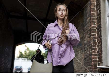 Frightened female is running alone at day time on street. Action. Woman afraid of rapist Frightened female is running alone at day time on street. Action. Woman afraid of rapist 82264713
