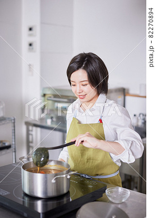 キッチンでカレーを作るエプロン姿の若い女性 キッチンでカレーを作るエプロン姿の若い女性 82270894