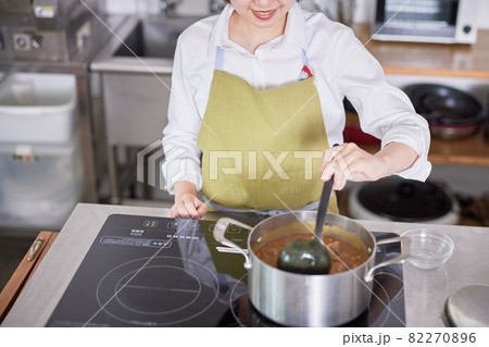 キッチンでカレーを作るエプロン姿の若い女性 キッチンでカレーを作るエプロン姿の若い女性 82270896