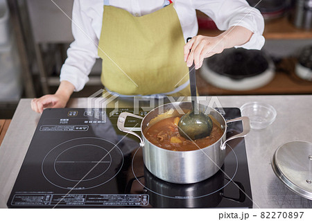 キッチンでカレーを作るエプロン姿の若い女性 キッチンでカレーを作るエプロン姿の若い女性 82270897