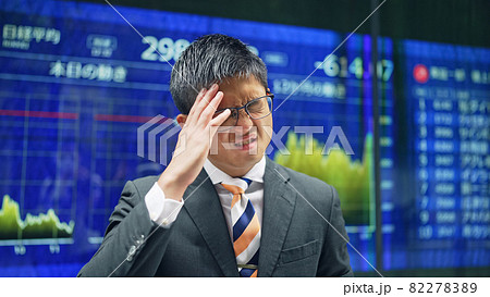 株価ボードの前で落ち込む男性 株価ボードの前で落ち込む男性 82278389