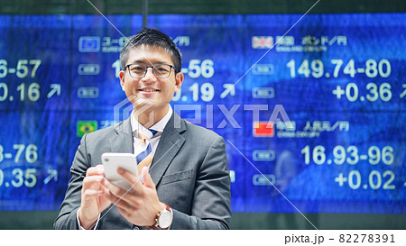 株価ボードの前で笑顔の男性 82278391