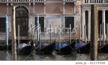 Empty black gondolas swaying on a pier close to the beautiful white facade Empty black gondolas swaying on a pier close to the beautiful white facade 82279560