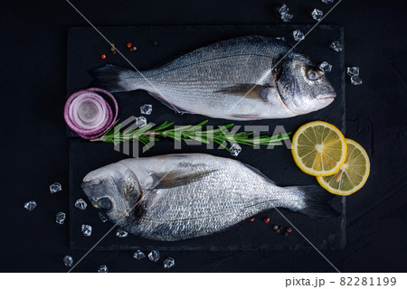 Raw Dorado lie on a black stone chopping Board. 82281199