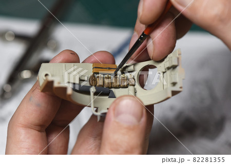 Close up of male hands painting and assembly scale model of a tank. 82281355