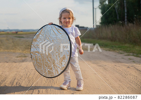 a toddler holds a reflector for the photographer. little helper assistant a toddler holds a reflector for the photographer. little helper assistant 82286087