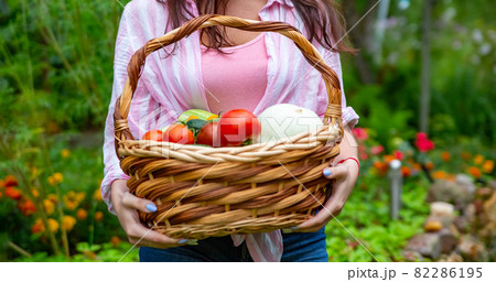 faceless happy smiling woman farmer hold a basket of vegetables from her garden. 82286195