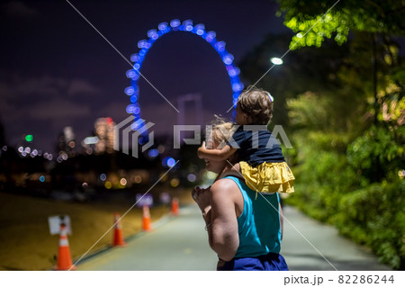 mom with a baby on her shoulders in the evening park against the background of the Ferris wheel mom with a baby on her shoulders in the evening park against the background of the Ferris wheel 82286244