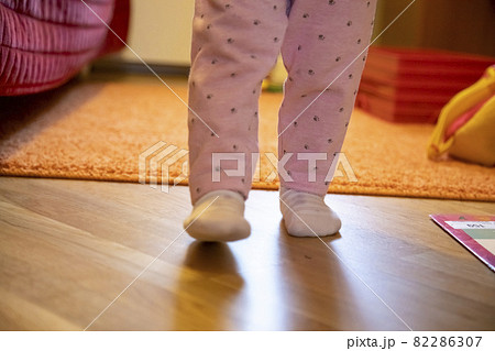 the legs of a small child are walking around the room. baby's first steps concept. no face the legs of a small child are walking around the room. baby's first steps concept. no face 82286307