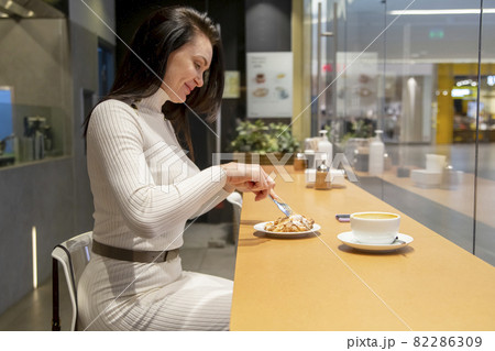 beautiful middle-aged woman eating a croissant in a cafe. lunch break beautiful middle-aged woman eating a croissant in a cafe. lunch break 82286309
