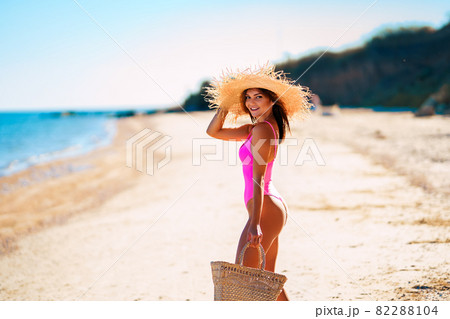Slim woman in pink swimsuit walking at ocean beach. summer vacation. Hair removal laser Slim woman in pink swimsuit walking at ocean beach. summer vacation. Hair removal laser 82288104