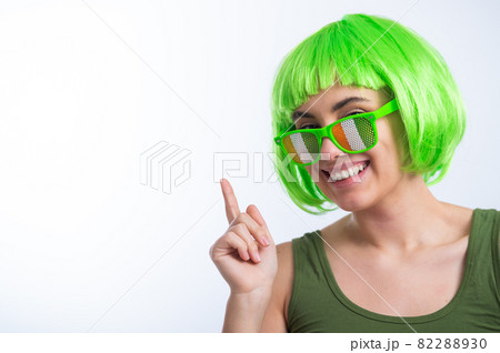 Cheerful young woman in green wig and funny glasses celebrating st patrick's day on a white background 82288930