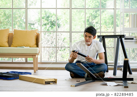 Handyman installing wooden bench in new house. House renovation service. Morning work atmosphere in the living room. 82289485