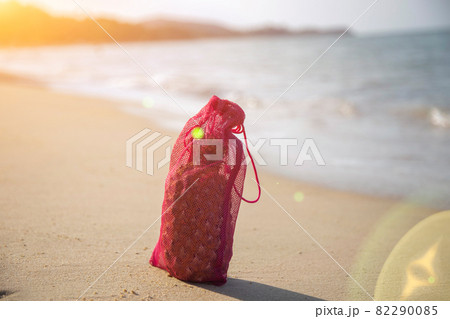 Mesh shopping bag with fruits stands on the sandy beach of the sea on a sunny day. ecology of the oceans concept Mesh shopping bag with fruits stands on the sandy beach of the sea on a sunny day. ecology of the oceans concept 82290085