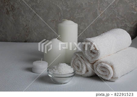 Spa treatments care home body llax massage. White candle towels in a roll of salt and scrub on a gray background with space for copyspace text. Beauty parlour Spa treatments care home body llax massage. White candle towels in a roll of salt and scrub on a gray background with space for copyspace text. Beauty parlour 82291523