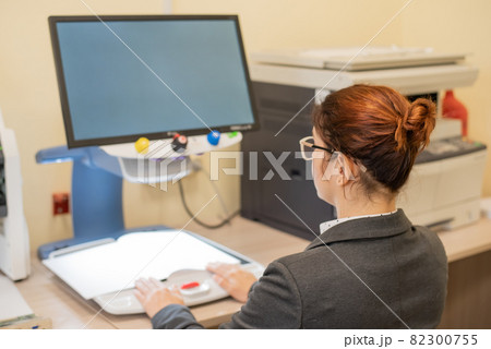 A visually impaired woman uses special reading equipment 82300755
