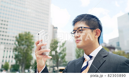 都市をバックにスマホを見るビジネスマン 82303890